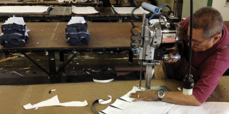 A cutter in the U.S. denim manufacturing chain cutting the jeans patterns from markers in Los Angeles, Calf.