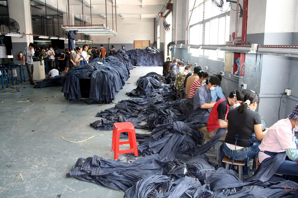 Denim manufacturing factory inside China in 2006. Jeans are hand-sanded for aging effects before washing.