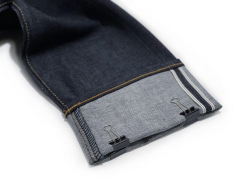 Raw denim selvedge jeans hem with clips to mark inseam length, removing the need for a measuring tape.