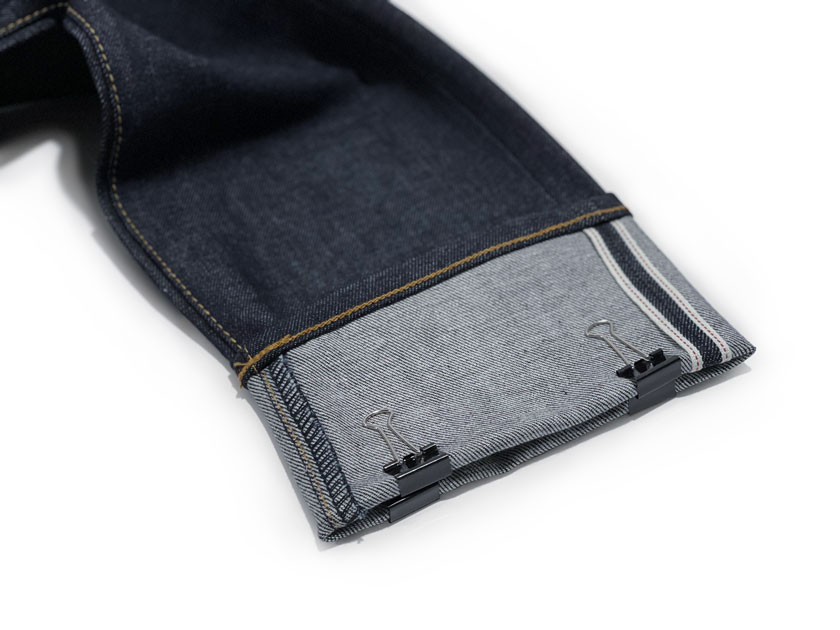 Raw denim selvedge jeans hem with clips to mark inseam length, removing the need for a measuring tape.