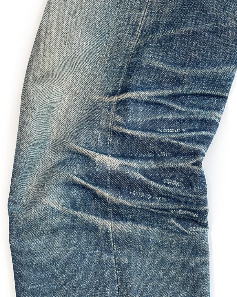 Side view of naturally formed denim stretch marks on the knees of raw denim jeans.
