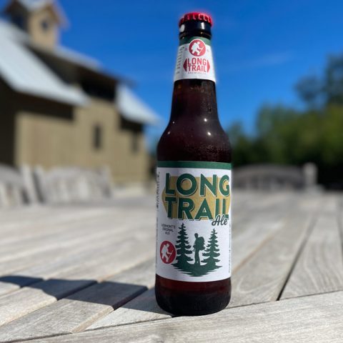 12-ounce bottle of Long Trail Ale by Long Trail Brewing Company with a Vermont house and woods in the background.