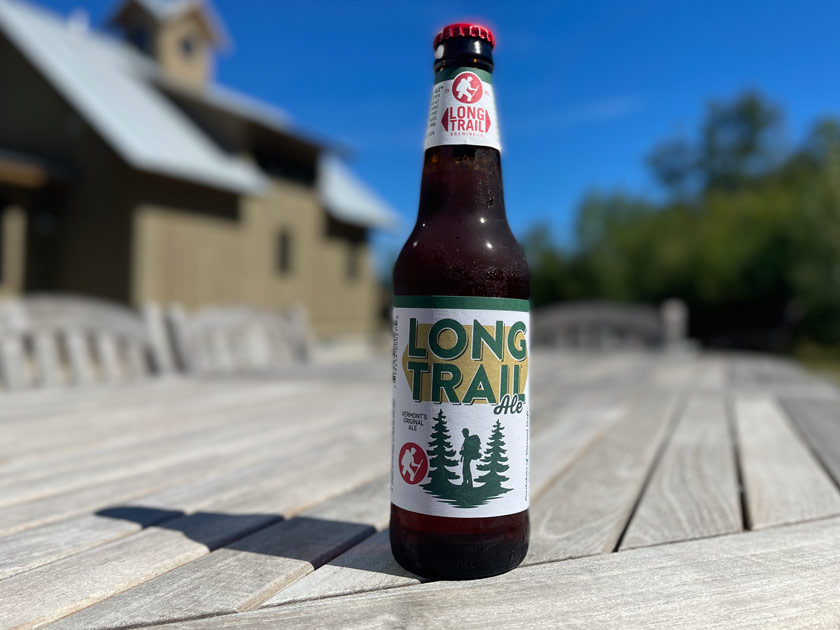 12-ounce bottle of Long Trail Ale by Long Trail Brewing Company with a Vermont house and woods in the background.
