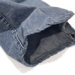 Close-up of a poorly chain-stitched hem on a pair of Levi's denim jeans, showing misalignment and puckering.