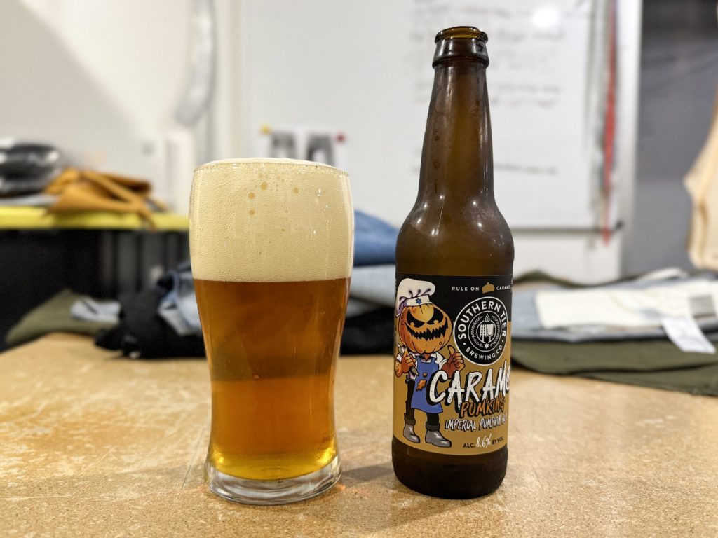 A 12 oz bottle and a glass of Southern Tier Brewing Company's Caramel Pumking Imperial Pumpkin Ale on a cutting table at Williamsburg Garment Company.