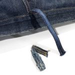 A pair of jeans showing a newly attached replacement belt loop beside the original worn, detached loop, highlighting professional repair work by the Williamsburg Garment Company's belt loop repair service.