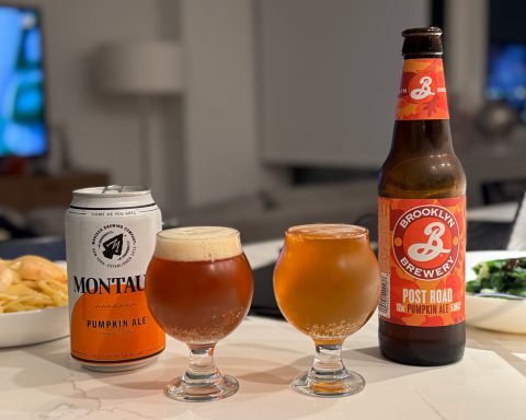 Two glasses on a table, left filled with Montauk Pumpkin Ale showing a darker hue and creamier head, right filled with Brooklyn Brewery Post Road Pumpkin Ale, lighter in color.