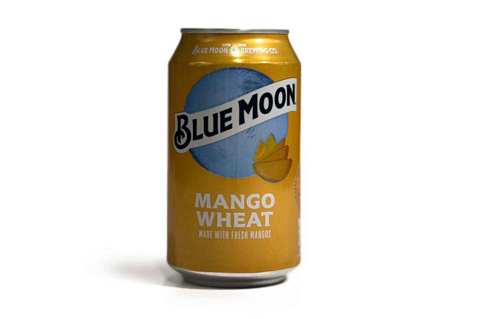 A can of Blue Moon Mango Wheat beer, photographed on a white background, for a Denimbmc.com blog review. The can features bright yellow-orange packaging with a mango illustration.