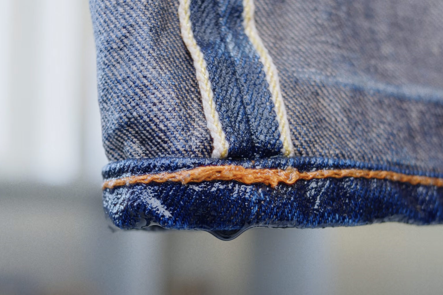 Close-up of wet raw denim jeans after washing, highlighting proper denim care techniques.