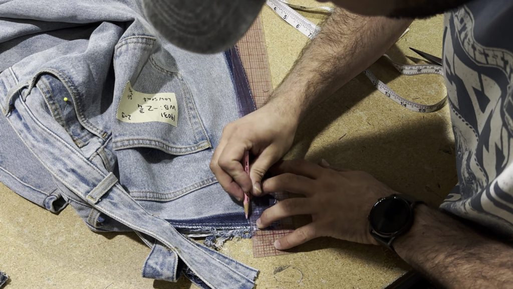 A tailor marks the amount to be removed from the center seam to take in the waist of jeans. Precise measuring ensures a perfect fit and maintains the original shape of the denim.