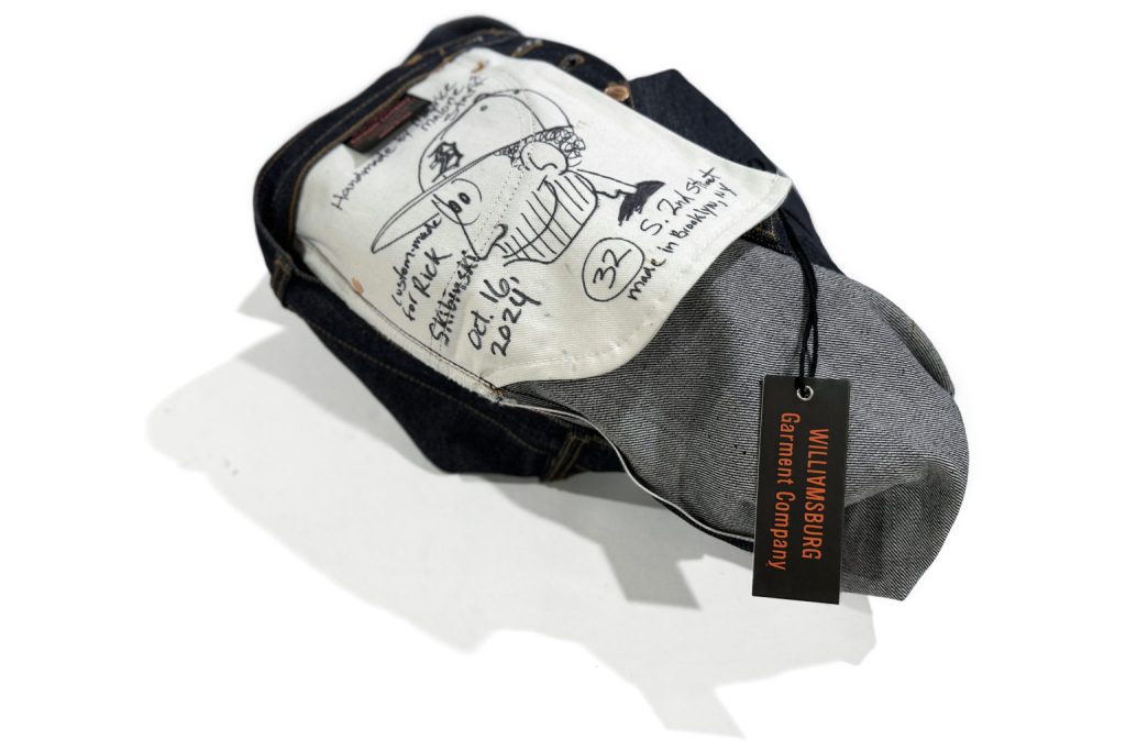 Signed handmade jeans with illustrated pocket bag and Williamsburg Garment Company tag, representing the upcoming denim workshop where attendees learn how to make jeans.
