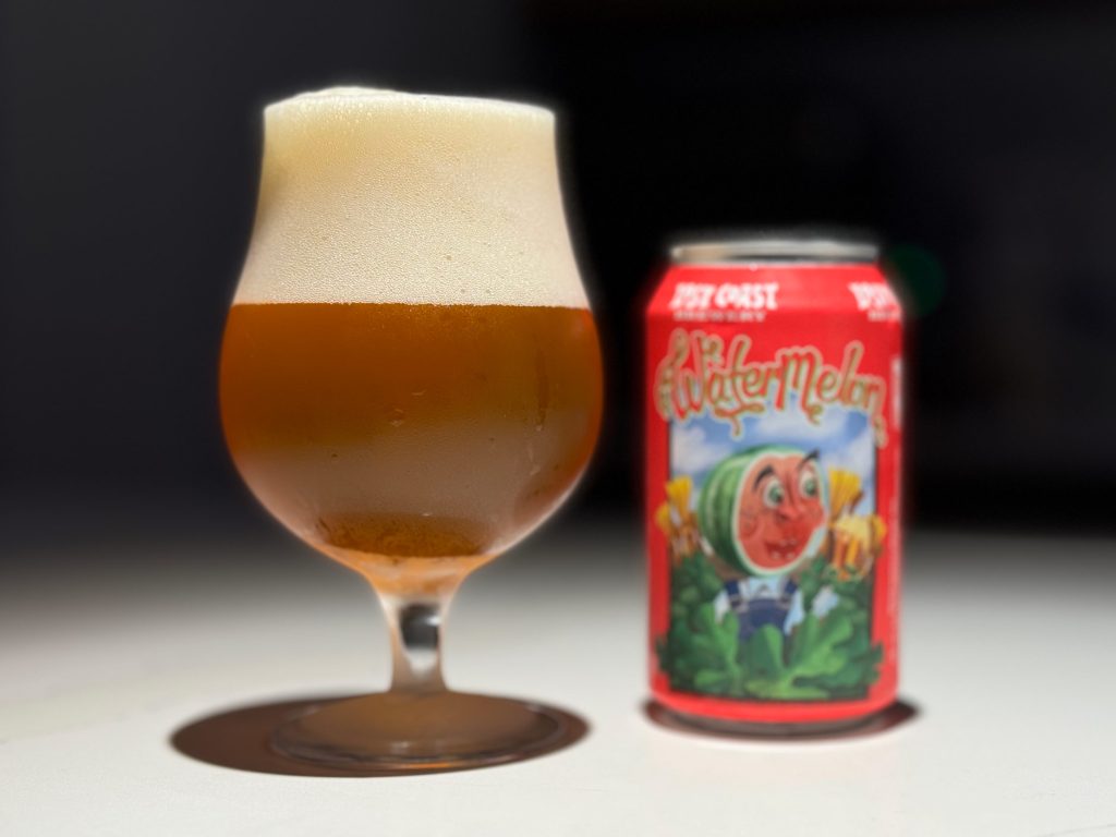 A full glass of Lost Coast Watermelon Wheat Ale with a thick, foamy head beside its bright red can