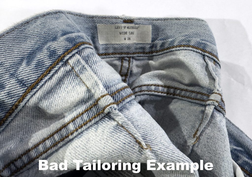 Inside view of jeans waistband showing bad tailoring with darts added to take in the waist