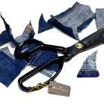 Guggenheim shears surrounded by freshly cut denim fabric pieces, demonstrating professional scissors for cutting denim.