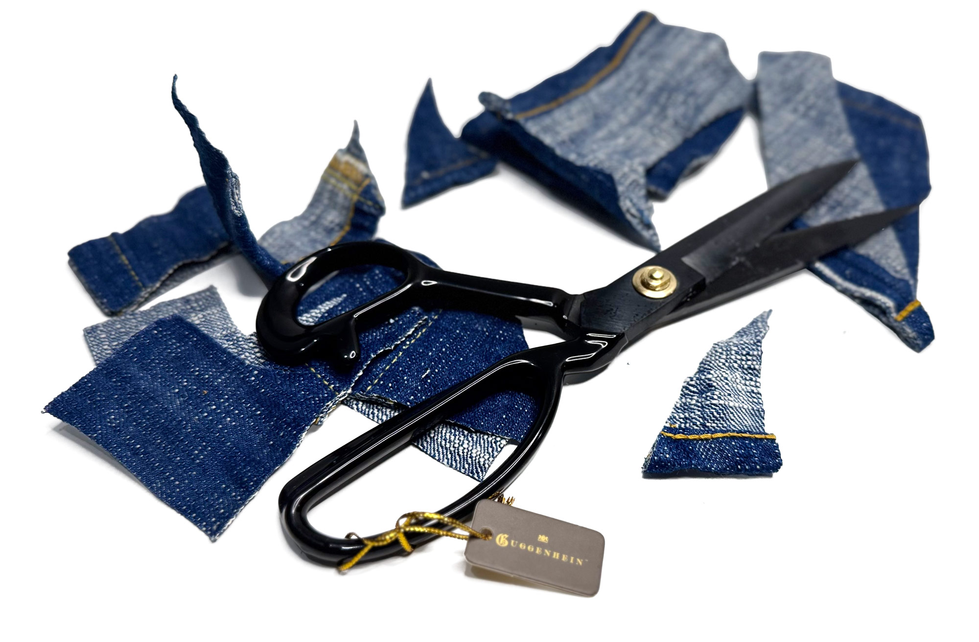 Guggenheim shears surrounded by freshly cut denim fabric pieces, demonstrating professional scissors for cutting denim.
